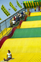 CTF001KK 006 001-White teen girl sitting on burlap sack slides down giant slide at county fair, Milwaukee, WI 