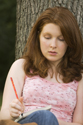 TEN911KK 001 001-Red-headed White teen girl leaning against tree trunk writes on her notebook, Riverwoods, IL 