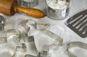 FOD801KK 001 001-Close-up of rolling pin, cookie cutter shapes, measuring cup with flour, and pancake turner on white pastry sheet   