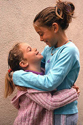 FAM675FM 004 001 -Smiling White girl wearing blue shirt hugs her smiling younger sister 